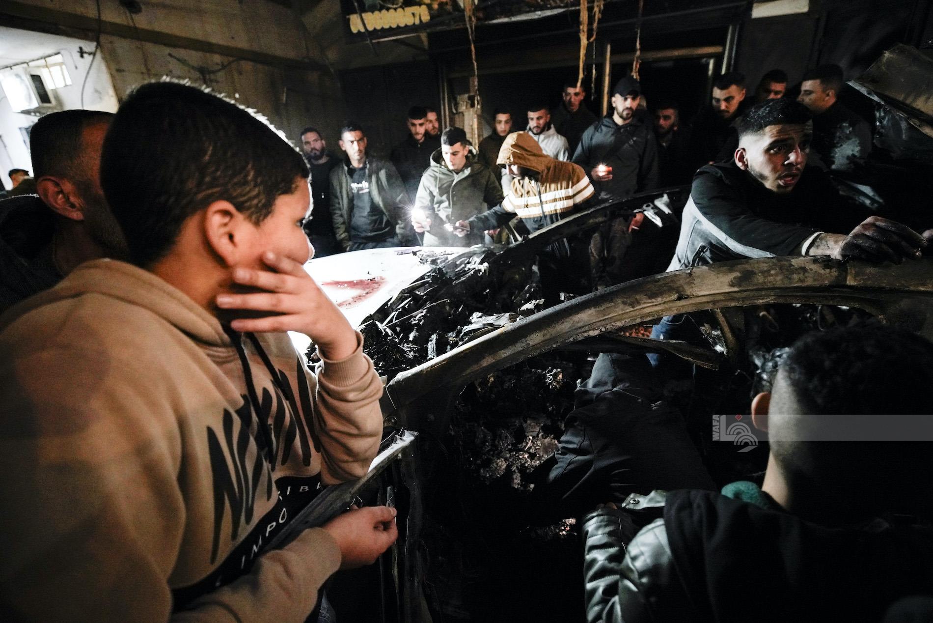 مواطنون يتفقدون المركبة التي قصفها الاحتلال الإسرائيلي في مخيم جنين (تصوير: محمد منصور/وفا)